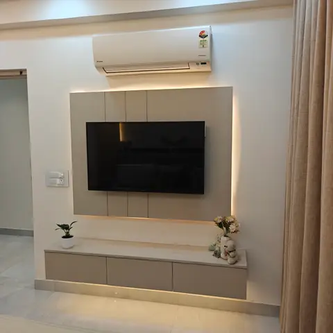 Backlit taupe TV feature wall with a fluted-front floating console styled with a small plant and toy figurines.