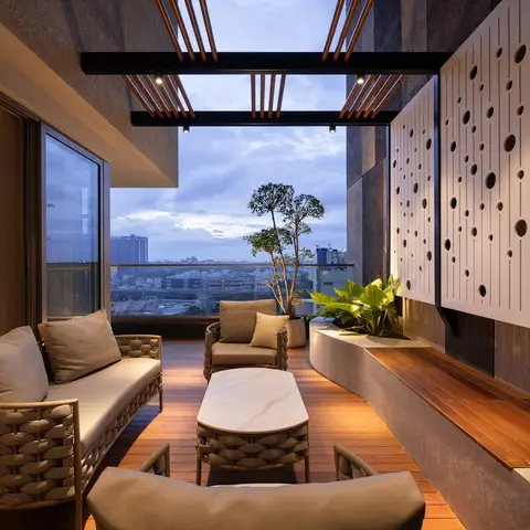 Balcony lounge with woven outdoor sofa seating around a marble-top coffee table, a wood deck floor, potted plants