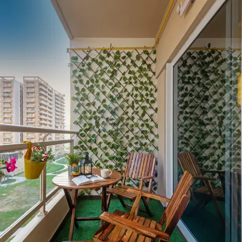 Balcony seating nook with a wooden folding table and chairs on artificial turf, a trellis wall trained with faux ivy