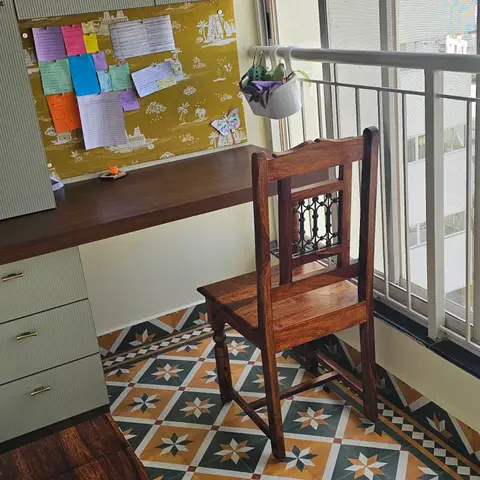 Balcony-turned-study nook with a bold star-patterned tile floor, a built-in wood desk with a corkboard of notes, a vintage carved wooden chair