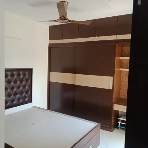 Bare bedroom at handover with a tufted dark-leatherette headboard panel, a box-storage bed with an undressed mattress