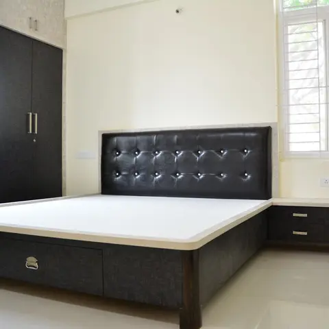 Bare king bed with a button-tufted black leatherette headboard and a drawer-fronted base