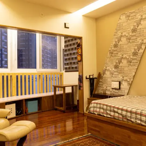 Bed built up on a wooden plinth with a plaid cover, set against a diagonally-cut monochrome cityscape wallpaper panel edged in timber beading