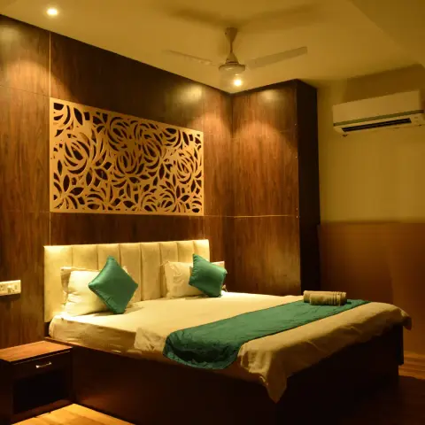 Bedroom clad floor-to-ceiling in dark walnut veneer with a backlit CNC-cut floral jaali panel above a channel-tufted cream headboard