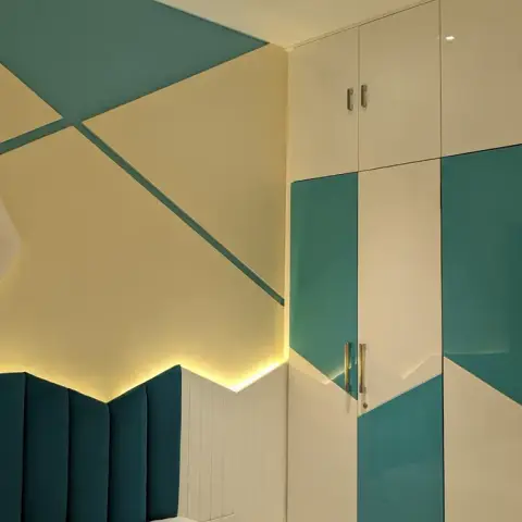 Bedroom corner where a channel-tufted teal headboard with concealed backlight meets angular teal-and-cream colour blocking that runs up onto the ceiling