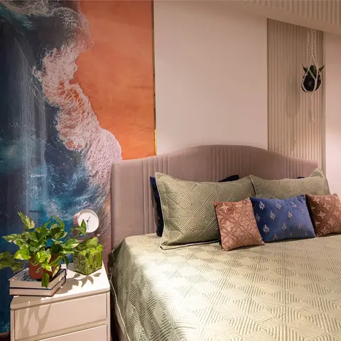 Bedroom corner where an aerial shoreline photo mural fills the side wall beside a blush channel-tufted headboard