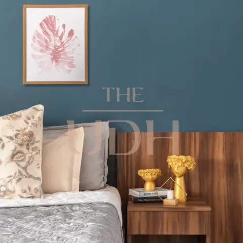 Bedroom corner with a deep teal accent wall, a wood-panel headboard, and a walnut nightstand styled with gold decor and a framed leaf print.