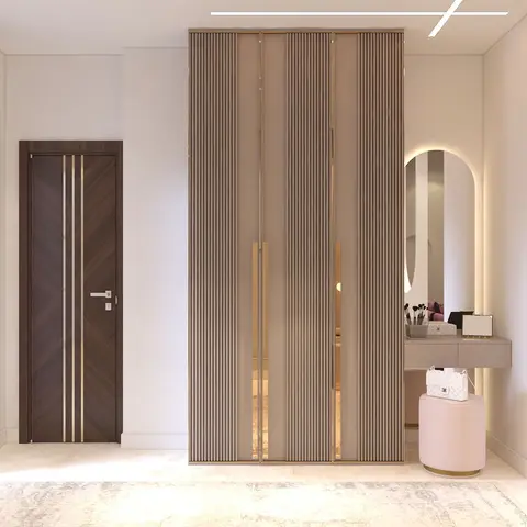 Bedroom corner with a floor-to-ceiling fluted wardrobe framed in gold trim beside an arched backlit vanity mirror and a pink velvet pouf.