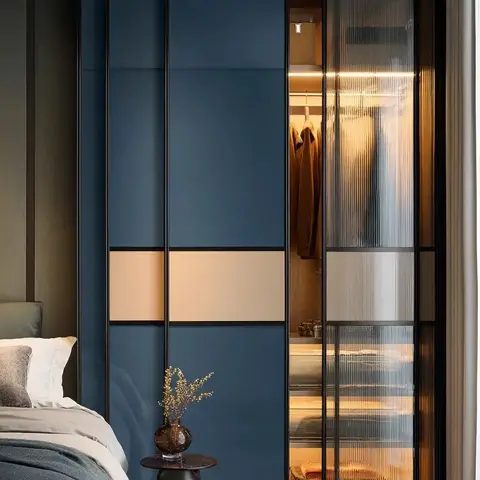 Bedroom corner with a navy-blue lacquer sliding wardrobe featuring a fluted-glass door that reveals an internally lit walk-in closet