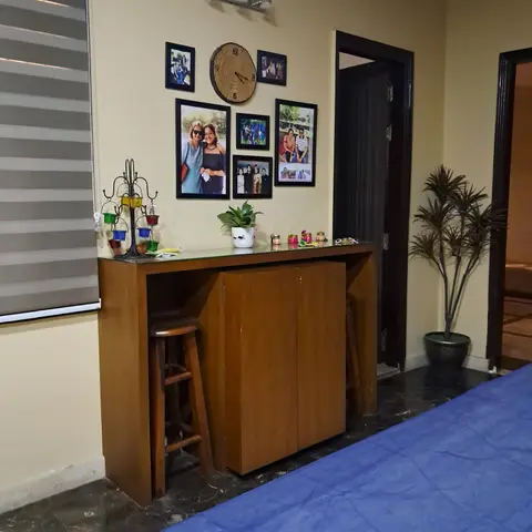 Bedroom corner with a wood bar-height console beneath a curated family photo gallery wall and a wood-slice clock.