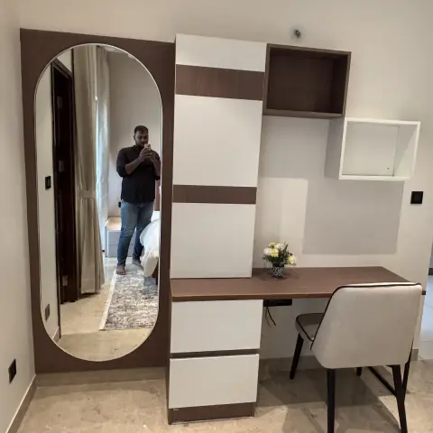 Bedroom dressing corner: a capsule full-length mirror on a walnut-laminate back panel next to a white-and-walnut study-cum-dresser unit with open cubes
