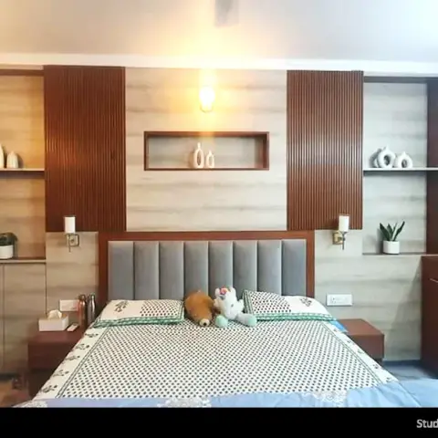 Bedroom headboard wall alternating walnut fluting with pale woodgrain laminate around lit display niches