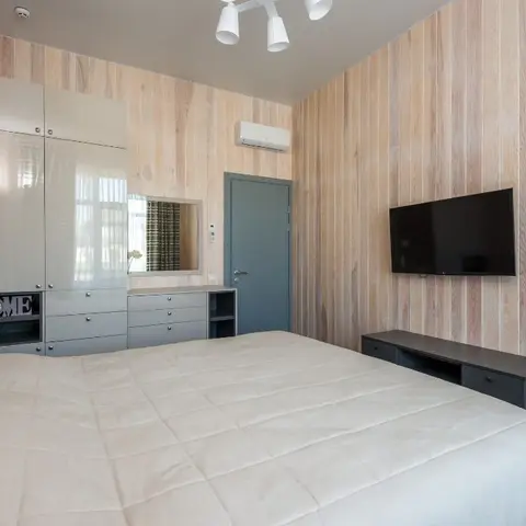 Bedroom lined floor-to-ceiling in whitewashed vertical pine planks, with a cream gloss wardrobe over a grey drawer chest