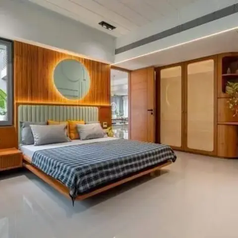 Bedroom lined in teak slat panelling with a round mirror above the padded headboard, a blue-check bedspread on a floating wooden bed