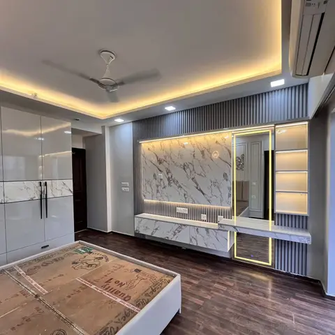 Bedroom nearing handover: a white-marble laminate feature panel with backlit LED and a floating console, framed by grey fluted panelling