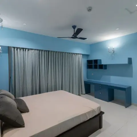 Bedroom painted mid-blue on every wall with a deeper blue band behind the dark wooden bed