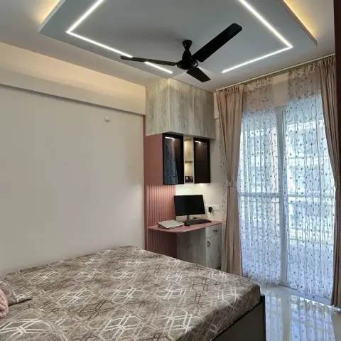 Bedroom shot from the bed corner up into a chevron-shaped POP ceiling with recessed linear LED strips and a warm cove, a black ceiling fan on the drop