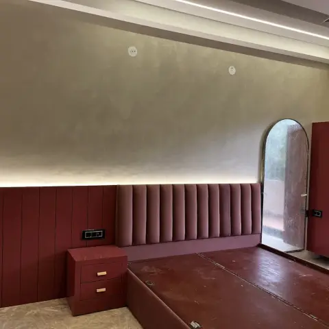 Bedroom still being handed over - a channel-tufted wine velvet headboard runs the length of the wall over a maroon vertical panelled dado