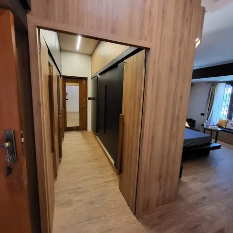 Bedroom suite with a wood-panelled walk-in wardrobe passage leading to the bed and a window seat bench.