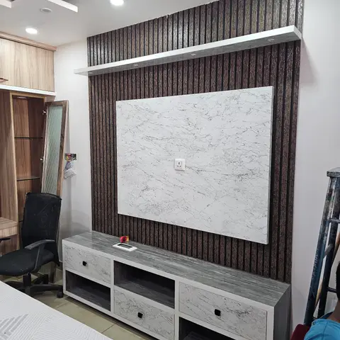 Bedroom TV feature wall with a bronze fluted panel backdrop, a marble-effect accent slab and a matching grey-marble-finish TV console.