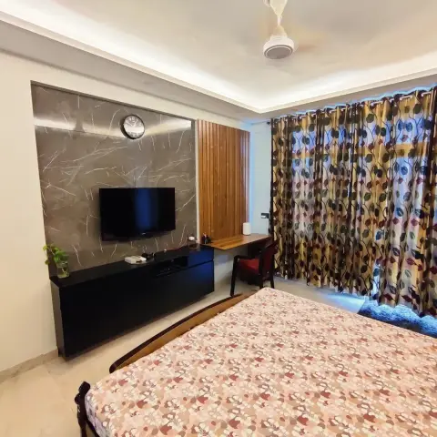 Bedroom TV wall in grey veined marble-look cladding with a black floating console
