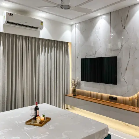 Bedroom TV wall in white marble-look slab with a curved fluted-teak return, a wall-hung grey console topped by a backlit timber ledge