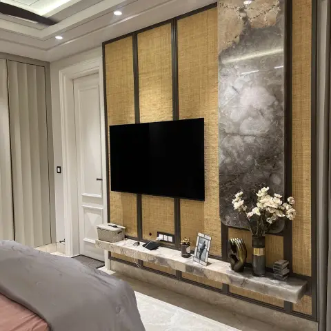 Bedroom TV wall of cane-webbing panels in slim black metal frames beside a grey marble slab strip