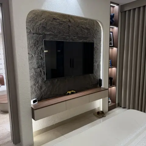 Bedroom TV wall of rough-split grey stone set in an arched recess of white textured plaster