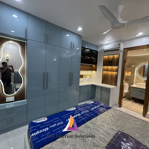 Bedroom under final staging with a glossy blue-grey wardrobe wall, a backlit fluted mirror niche, a built-in study desk