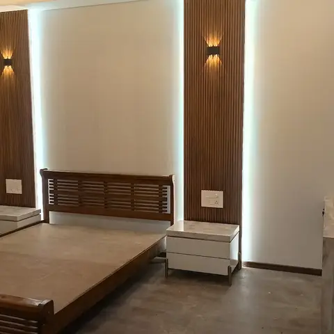 Bedroom under finishing with a wood slat-back bed frame flanked by fluted wood wall panels and sconce lighting, marble-top nightstands