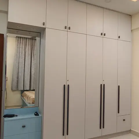 Bedroom wardrobe run in flat white laminate with long black bar handles and lofts
