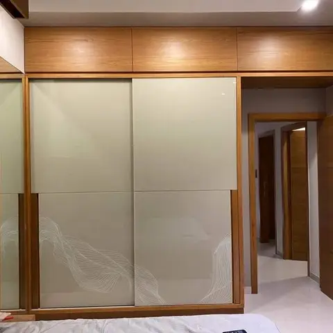 Bedroom wardrobe wall with a wood-framed sliding wardrobe featuring frosted glass shutters etched with a wave pattern