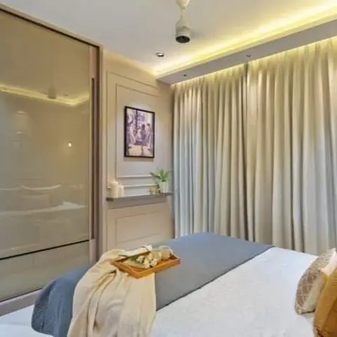 Bedroom where a bronze-tinted glass sliding wardrobe reflects the made bed, cream drapes run the full end wall under a warm cove