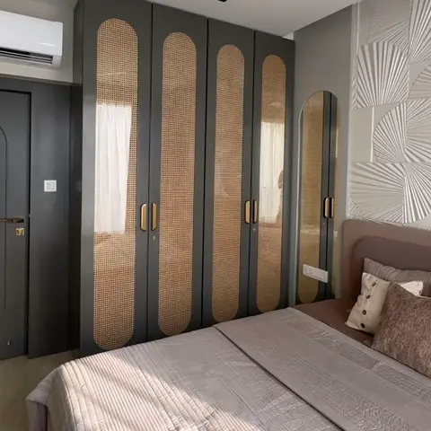 Bedroom where a charcoal wardrobe run carries tall arched cane-webbing inserts with brass bar pulls, beside a matching charcoal door