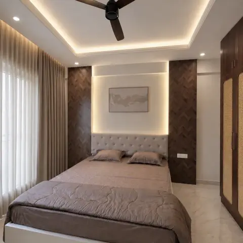 Bedroom where a grey tufted headboard sits in a backlit recessed niche flanked by two dark herringbone timber panels