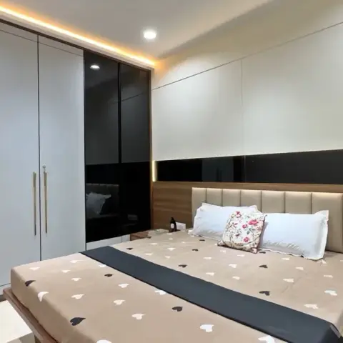 Bedroom with a beige channel-tufted upholstered headboard, walnut-finish wall paneling with a black glass accent band