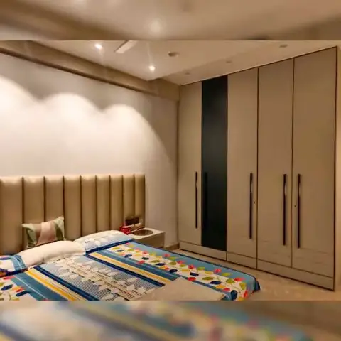 Bedroom with a beige channel-tufted headboard, a colorful striped bedspread, and a tall wardrobe with a black accent door panel