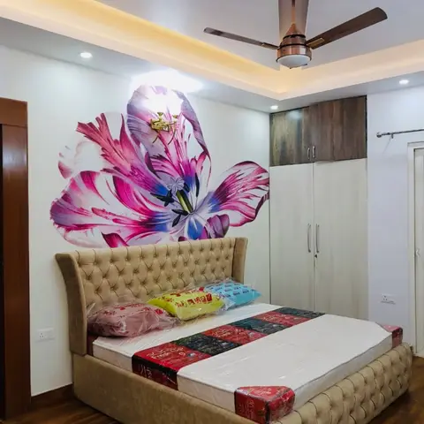 Bedroom with a beige tufted wingback bed still wrapped for delivery, a large pink tulip mural on the headboard wall, wood-finish wardrobe