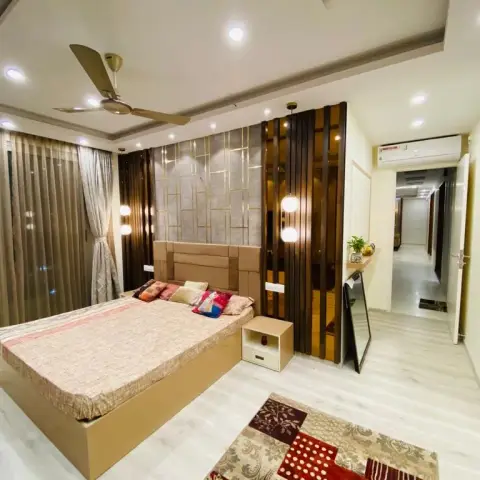 Bedroom with a beige upholstered headboard against a grey panel inlaid with thin gold lines