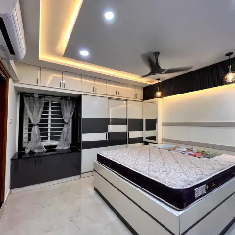 Bedroom with a black-and-white two-tone sliding wardrobe, a backlit textured accent wall behind the bed with hanging pendant lights, a cove-lit ceiling