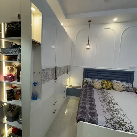 Bedroom with a blue channel-tufted upholstered headboard against an arched panel-moulded wall, twin pendant lights over bedside ledges