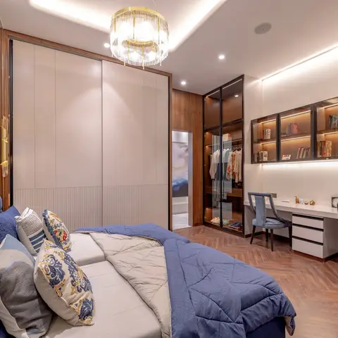 Bedroom with a blue tufted velvet headboard, a gold multi-tier chandelier, a glass-front walk-in wardrobe