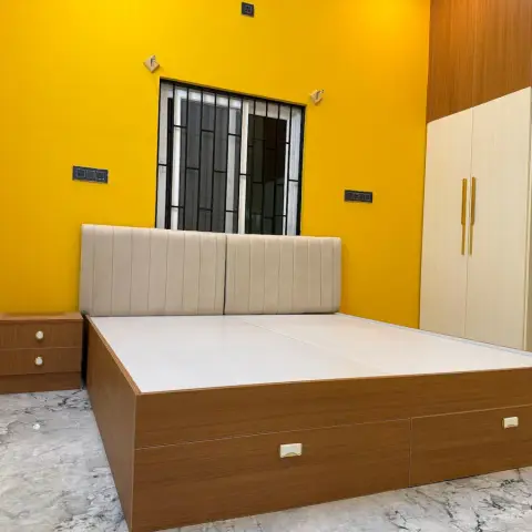 Bedroom with a bold yellow accent wall, a tufted cream upholstered headboard, a wood storage bed with drawer fronts, and a matching wardrobe with mirror.