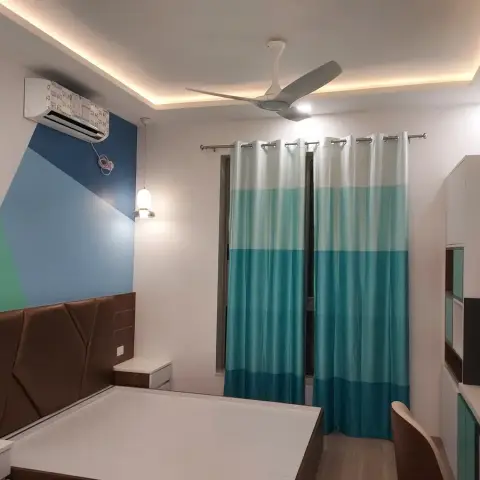 Bedroom with a brown faceted upholstered headboard running the width of the bed, angular green-and-blue colour-blocked paint above it