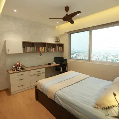 Bedroom with a built-in study run along the window wall - open bookshelf over a desk plus a six-drawer chest - beside a dark wood bed