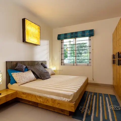 Bedroom with a burl-wood veneer bed and matching wardrobe wall, sculptural leaf-motif bedside lamps, a backlit abstract wall art panel, a teal roman blind