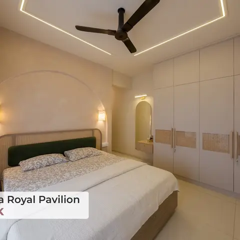 Bedroom with a cane-frame headboard and olive-green velvet backrest set into an arched textured-plaster alcove