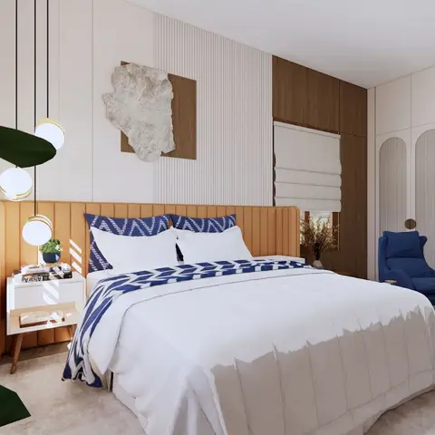 Bedroom with a caramel channel-tufted headboard, arched fluted ivory wardrobes with brass disc pulls, a cobalt wing chair and matching ottoman in the corner