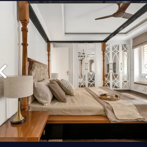 Bedroom with a carved wood four-poster bed and matching nightstand, a white wainscoted wall