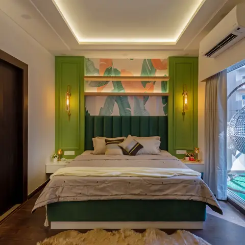 Bedroom with a channel-tufted bottle-green velvet headboard running wall to wall, banana-leaf mural wallpaper above it lit by two backlit oak shelves